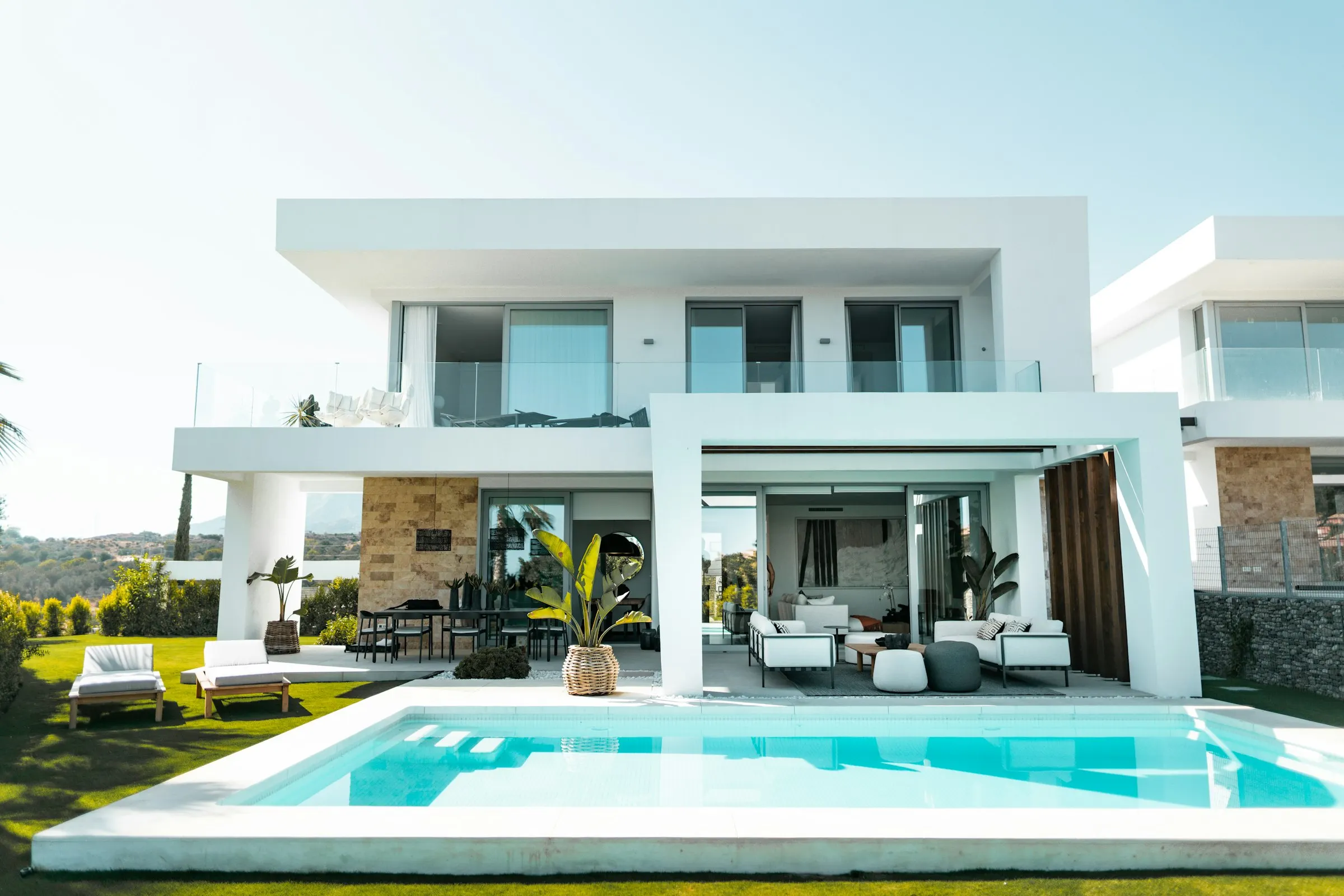 Luxury modern house exterior with swimming pool and landscaped yard on a clear day